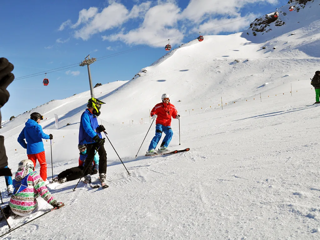 Skifahrende an der Bergstation vor der Felskulisse.